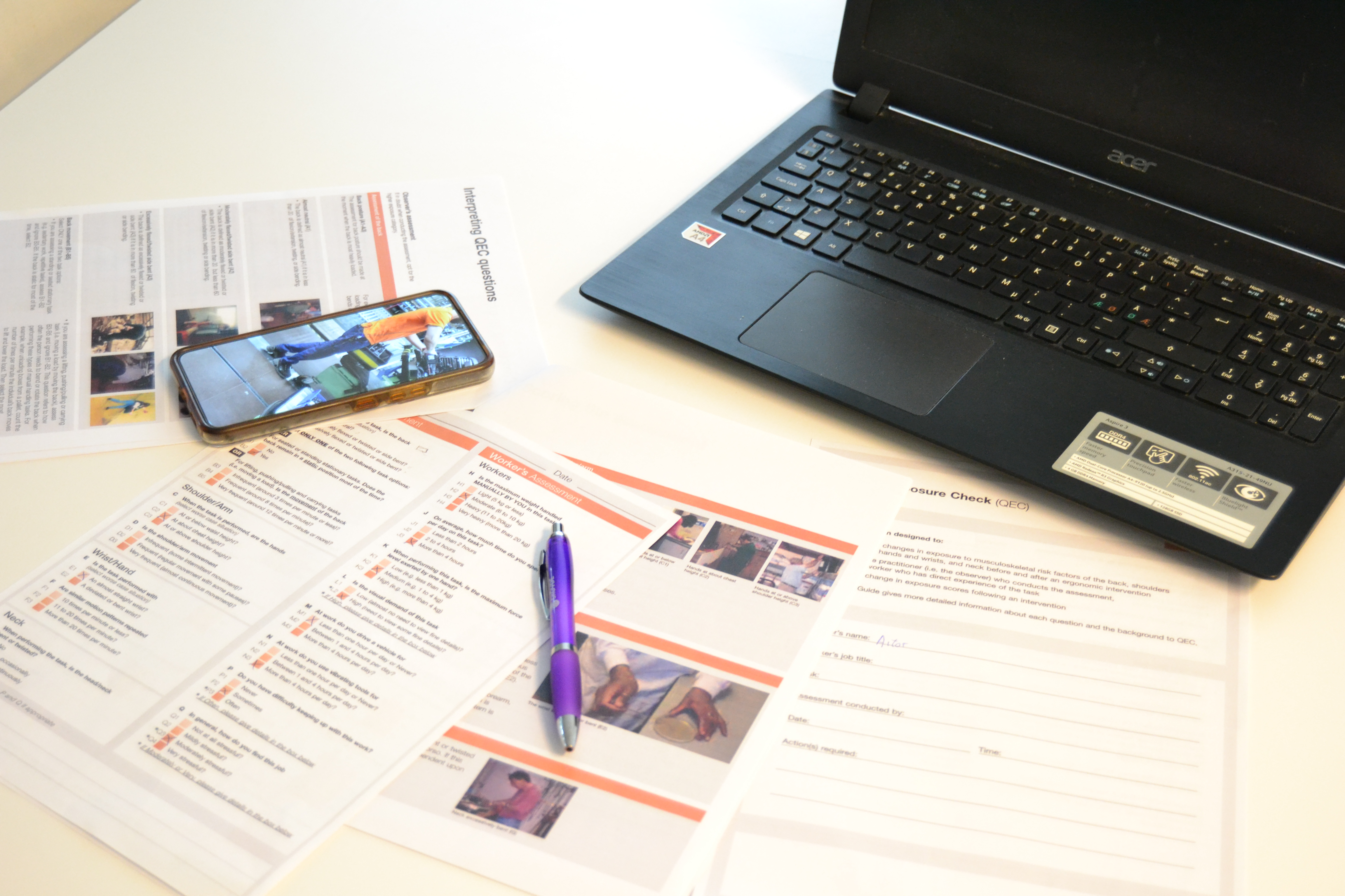 Ergonomist using phone and QEC paper forms with laptop in the field